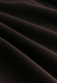 Teksturowana czarna tkanina z miękką, gładką powierzchnią, prezentująca fałdy i subtelny połysk, podkreślająca jej głębię i bogactwo koloru.