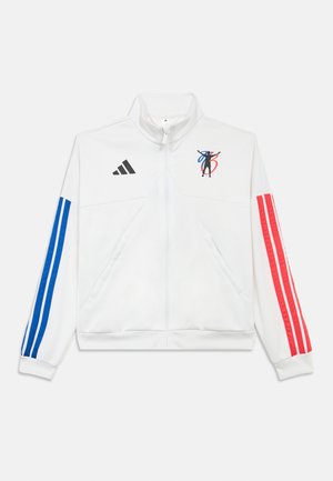 Bílá bunda na zip s modrými a červenými pruhy na rukávech, černým logem Adidas a grafickým motivem na hrudi. Měkký materiál a běžný střih.