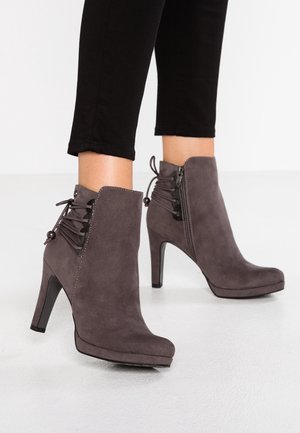 Bottes basses en daim gris à talon haut, dotées d'une fermeture éclair latérale et d'un détail en lacets à l'arrière. Texture lisse et design à bout arrondi.