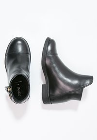 Bottines en cuir noir avec un bout rond, un talon bas et un zip sur le côté. Présentent une texture lisse et des détails de couture subtils.