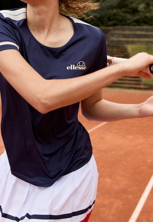 Navy athletic t-shirt with short sleeves, curved neckline, and a logo. Paired with a white skirt featuring black and colored stripes.