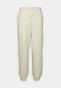 Pantalones de chándal color crema fabricados con tejido suave, con una cinturilla elástica con cordón, bolsillos laterales y puños acanalados.