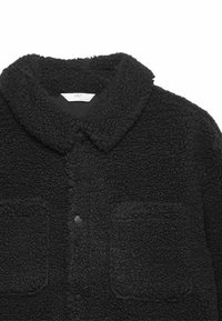 Sort fleecejakke med krave, knaplukning og to forlommer; tekstureret stof med et blødt, fluffy udseende.