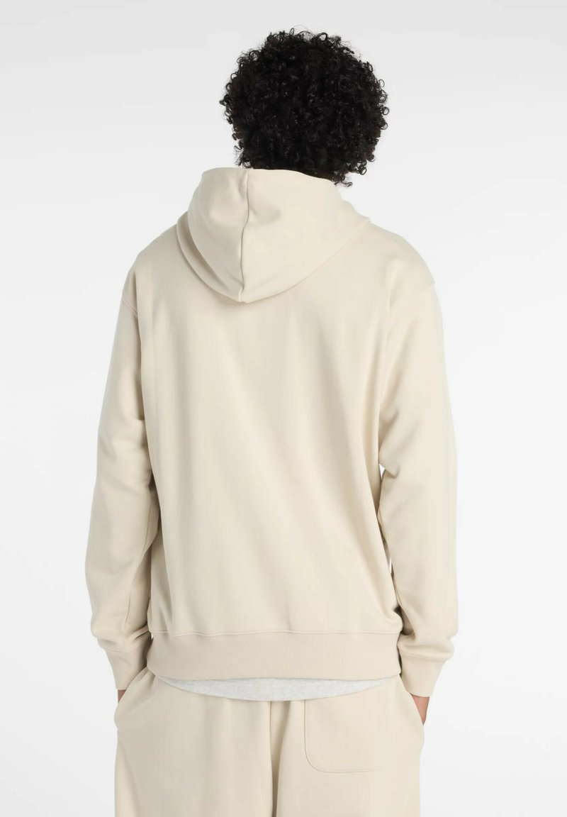 Hellbeige Kapuzenpullover mit weichem Textil, gerippten Bündchen und lässigem Schnitt. Schlichte Gestaltung, sichtbare Nähte an den Säumen.