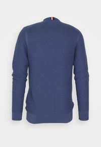 Maglione navy blue texturizzato con un motivo a costine. Presenta un colletto rotondo con un accento tricolore sul retro. Maniche lunghe.