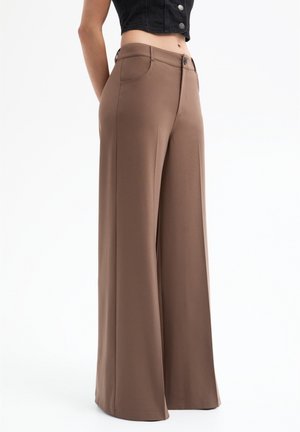 Braune weit geschnittene Hose aus glattem Stoff, mit Knopfverschluss und Fronttaschen, die eine taillierte Passform und fließende Silhouette zeigt.