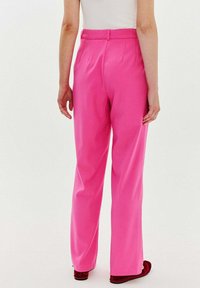 Różowe spodnie o prostym kroju, wykonane z gładkiego materiału, z fałdami z przodu i dopasowaną talią. Widok z tyłu pokazuje minimalne detale.