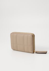 Beige glidelomme med quiltet design, med glitrende gullfarget glidelås i metall og en glatt overflate. Kompakt rektangulær form.