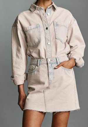 Lichtroze denim shirtjurk, met een knoopsluiting, twee voorzakken, een ceintuur in de taille en een rafelige onderkant met een relaxte pasvorm.