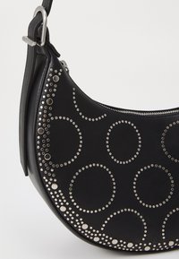 Black leather handbag with circular silver studs and accents. Slightly curved shape with a zipper closure and detachable strap.