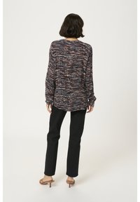 Blusa a maniche lunghe con un motivo astratto nei toni del navy, rosso e crema; vestibilità rilassata; tessuto leggero. Abbinata a pantaloni slim leg neri e sandali.