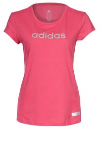 Camiseta de manga corta rosa, hecha de algodón, con cuello redondo. Presenta el logo plateado de "adidas" en el pecho y una pequeña etiqueta en la parte inferior.