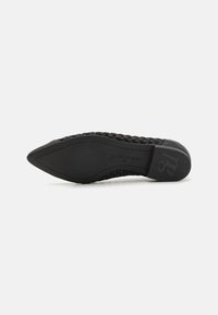 Chaussure plate tissée noire avec un bout pointu, semelle en caoutchouc et logo en relief sur le talon. Tige texturée pour flexibilité et confort.