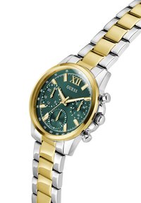 Montre à cadran vert avec un bracelet en métal doré et argenté, dotée de sous-cadrans chronographiques et d'un grand numéro 12. Nom de la marque "Guess" affiché.