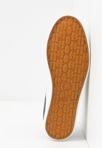 Semelle de chaussure en caoutchouc orange avec des motifs hexagonaux et rectangulaires et un logo circulaire près du talon, taille 37 indiquée.