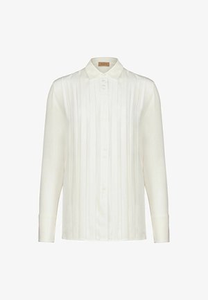 Blusa bianca a maniche lunghe con pieghe verticali, chiusura frontale con bottoni, colletto appuntito e polsini.