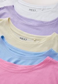 Five folded cotton t-shirts in white, lavender, cream, blue, and pink with round necks and Next brand labels.