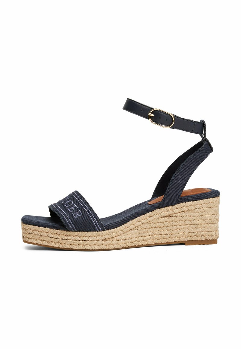 Sandalo con tacco a cuneo blu navy con tomaia in tela, suola in juta stile espadrille, cinturino alla caviglia con fibbia regolabile e dettagli ricamati sul cinturino.