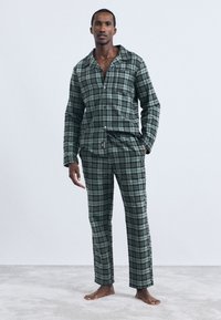 Πράσινο καρό σετ πιτζάμας από μαλακό ύφασμα, που περιλαμβάνει κουμπωτή μπλούζα και παντελόνι με κορδόνι και πλαϊνές τσέπες σε άνετη γραμμή.