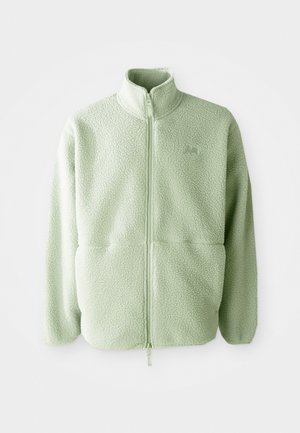 Lysegrønn fleecejakke med høy krage, hel glidelås og teksturert overflate; har to frontlommer og en liten logo.