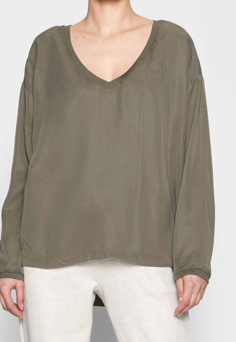 Maglietta verde oliva a maniche lunghe con scollatura a V profonda e vestibilità comoda. Realizzata in tessuto morbido, presenta maniche ampie e un orlo dritto.