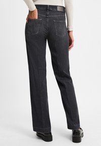 Černé džíny z denimu s rovnou siluetou, obsahující dvě zadní kapsy a texturovaný pas. K outfitu se hodí matné černé boty.