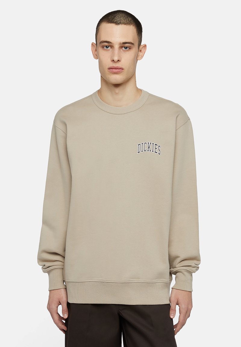 Sudadera beige hecha de una mezcla de algodón, con cuello redondo acanalado, mangas largas y un logo bordado en el lado izquierdo del pecho.