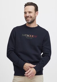 Sudadera navy hecha de algodón, con puños y cuello acanalados, y con texto bordado multicolor "MCMXXIV FQ1924" en la parte frontal.
