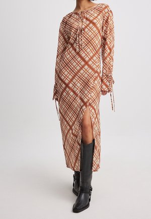 Brun ternet maxi-kjole med frontknytte, lange ærmer og side-slids. Matcher med sorte knæhøje støvler. Glat stofstruktur.