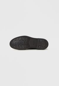 Black rubber sole of a shoe with chevron tread pattern and brand name GANT visible in center, size 41 indicated.