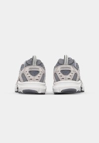Adidași gri din materiale de plasă și piele întoarsă, cu o talpă albă căptușită, guler căptușit și accente cu model pe călcâi.
