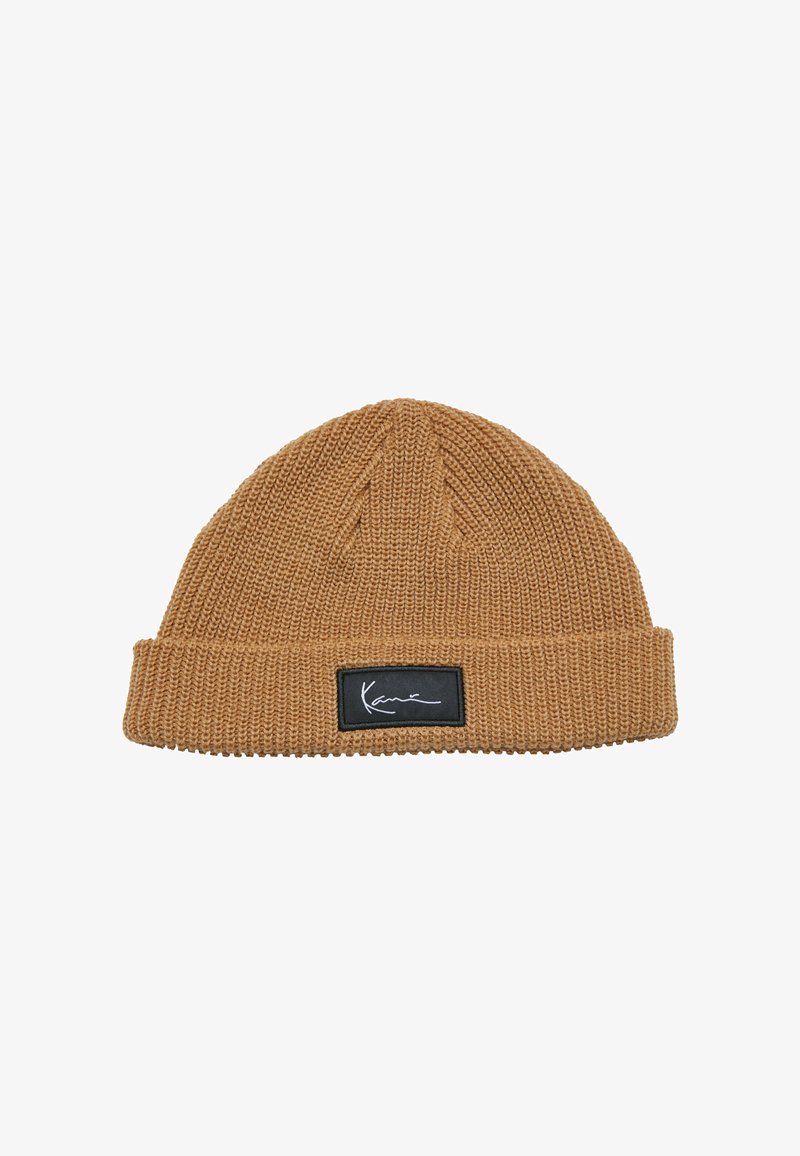 Beanie tricotat maro cu manșetă pliată. Notabil pentru modelul său texturat și un eticheta rectangulară neagră cu detalii semnate în alb.