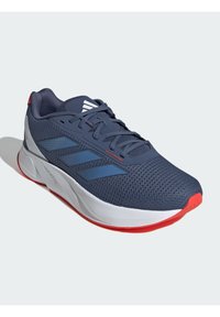 Scarpa atletica in rete blu navy con accenti rossi, suola bianca e strisce blu. Presenta un design con lacci e colletto imbottito per il comfort.