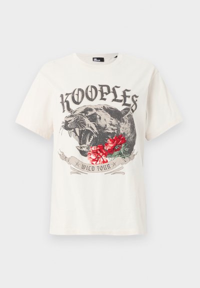 Λευκό T-shirt με μαύρη πάνθηρα που βρυχάται, κόκκινα τριαντάφυλλα, το κείμενο "KOOPLES" πάνω και ένα πανό με τις λέξεις "WILD TOUR" κάτω στο κέντρο μπροστά.