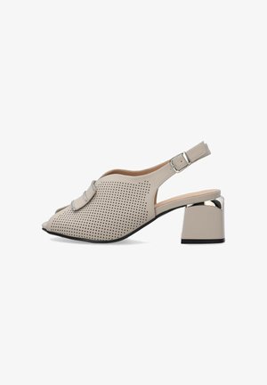 Beige åben-tå slingback sko med perforeret læder, sølvspænde, blokhæl med metallisk detalje og lav sål.