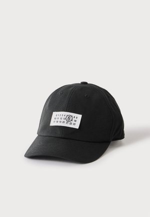 Casquette de baseball noire avec une étiquette rectangulaire blanche affichant les chiffres de 0 à 23, le chiffre 6 étant entouré au centre.