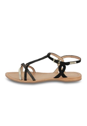 Sandalo in suede nero con cinturini incrociati, dettaglio metallico, suola piatta anteriore, cinturino alla caviglia regolabile e soletta beige.