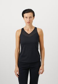 Svart tank topp med V-hals, med gjennomsiktige mesh-panel detaljer foran. Laget av glatt, myk stoff med en tettsittende design.