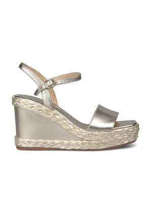 Sandalo a cuneo in oro metallico con soletta in juta intrecciata, cinturino alla caviglia regolabile e design a punta aperta. Texture liscia e forma snella.