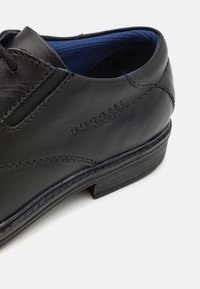 Czarne skórzane buty o gładkiej fakturze, z kontrastowym niebieskim wnętrzem i z logotypem "bugatti" po boku. Solidna czarna podeszwa.