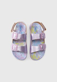 Δύο σανδάλια από μεταλλικό δέρμα λεβάντας με δύο ρυθμιζόμενες αγκράφες. Τα πέλματα διαθέτουν ένα παστέλ αφηρημένο μοτίβο με αποχρώσεις του μπλε και του κίτρινου.