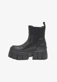 Botines negros hasta el tobillo con plataforma gruesa, hechos de cuero liso y paneles de tela elástica, con una suela gruesa y texturizada con marca.