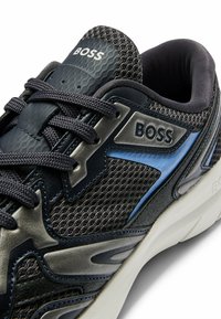 Baskets de sport bleu foncé avec des détails en mesh, des accents en cuir texturé, une marque en argent et une semelle rembourrée.