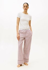 Witte top met korte mouwen, gecombineerd met rood-witte geruite pyjamabroek, met een gebrandmerkte tailleband, een relaxte pasvorm en wijde benen.