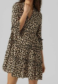 Robe à imprimé léopard en beige et noir, dotée d'un décolleté en V, de manches trois-quarts et d'un design à volants en étages. Tissu léger avec une texture subtile.