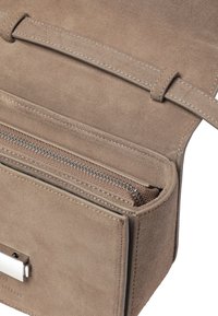 Beige mokkanahkainen käsilaukku, jossa on vetoketjullinen lokero ja hopeanväriset metalliosat. Laukun sisäpuolella on useita korttipaikkoja ja pehmeä pinta.