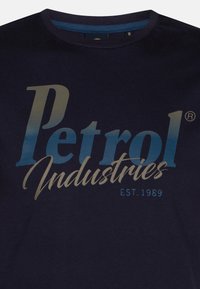 Marineblå bomulds T-shirt med et gradientgrafik, der har "Petrol Industries" med store bogstaver og "EST. 1989" med mindre bogstaver nedenfor.