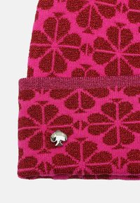 Gebreide beanie in felroze met rode bloempatronen; heeft een zilveren metalen logo-accent op de boord. Zachte textuur en een goede pasvorm.
