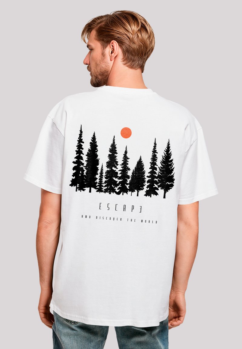 White t-shirt featuring a black forest silhouette and an orange sun graphic. Text below reads "ESCAPE AND DISCOVER THE WORLD."