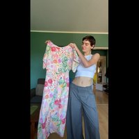 Maxi-jurk met bloemenpatroon in roze, geel, groen en blauw op een lichte achtergrond; met korte mouwen en ronde halslijn.
